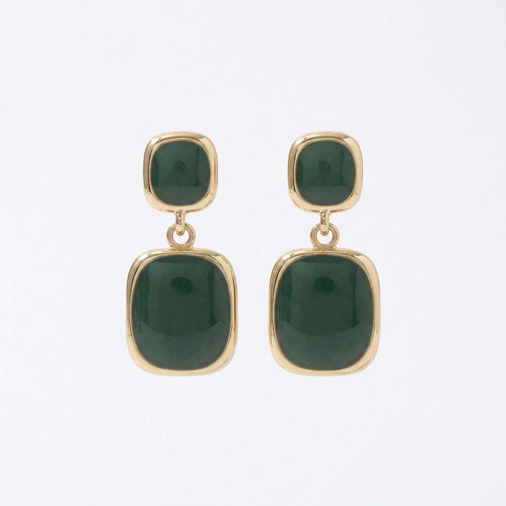 Green earrings with gold accents on a black earring card.
